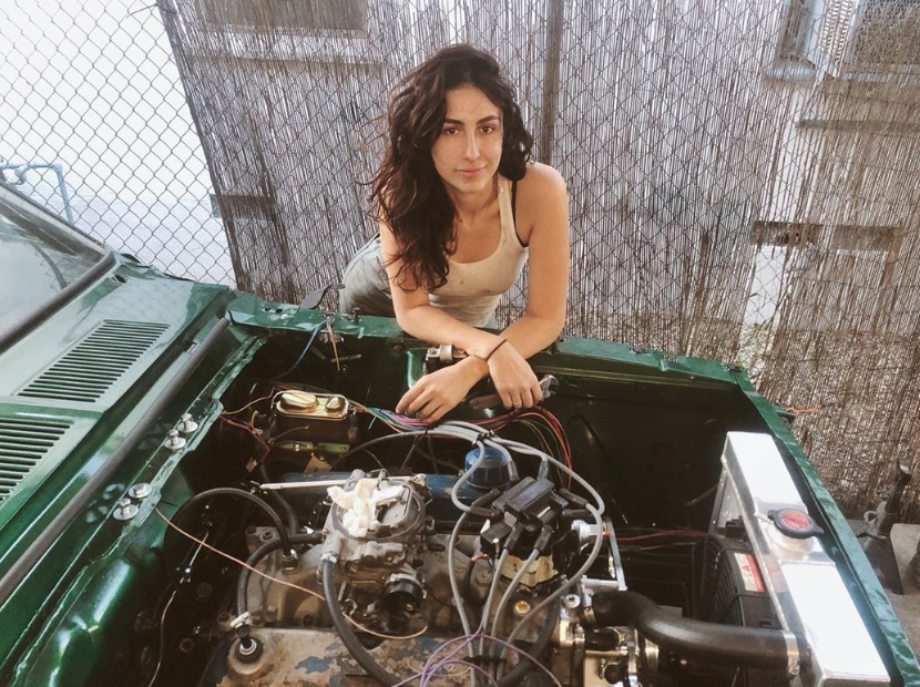 women leaning over car engine